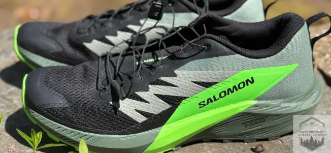 view of both salomon sense ride 5 shoes on a wall. Revealing the high heel stack height and higher heel to toe drop