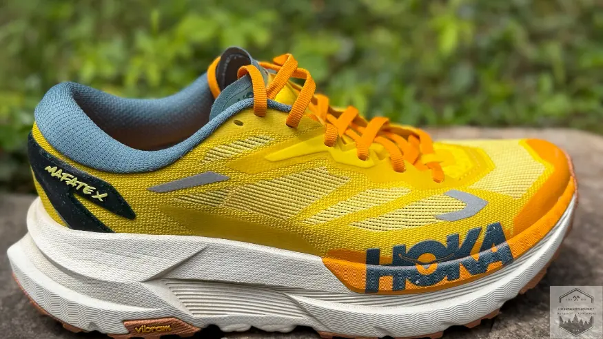 Side view of the Hoka Mafate X resting on a stone wall