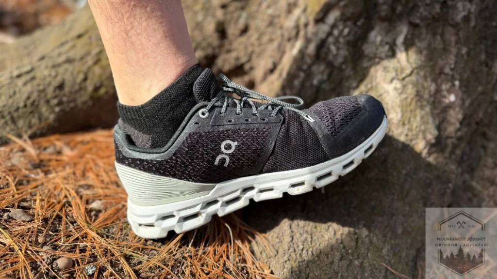 Side view of the On Cloud 6 resting against a tree trunk, showcasing the low-profile CloudTec pods and the sleek, breathable engineered mesh upper in a natural setting.